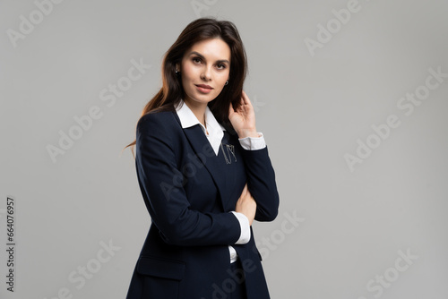 Young businesswoman wearing formal style suit. Business lady touching her brunette hair. Adorable ceo manager. Intelligent woman glamour posing. Beautiful female employer