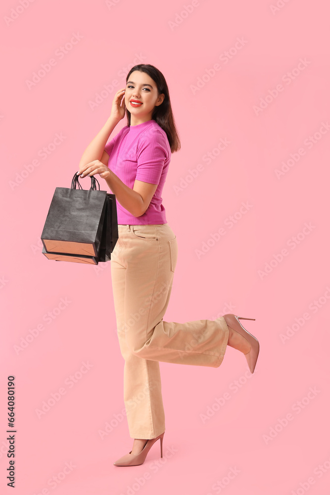Beautiful young woman with shopping bags on pink background. Black Friday sale
