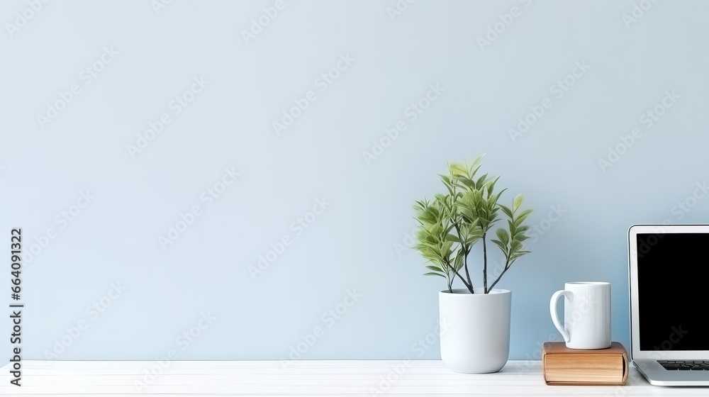 Close up view of creative workspace with blank screen computer, mug, tree pot and copy space on white table with shelf on light blue wall