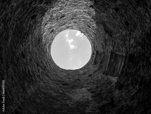 Stone well hole, old construction from inside, brick walls and blue sky background, fall down in the well concept photo