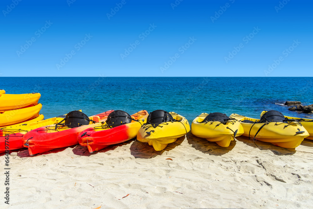 Red and yellow kayaks on the beach with the ocean and sky in the background Red and yellow kayaks on the beach with the ocean and sky in the background