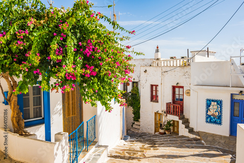 Typical narrow street with Greek architecture and houses decorated with flowers in Plaka village, Milos island, Cyclades, Greece