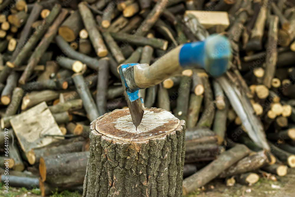 Old axe standing against a piled pieces of firewood stucked in tree stump Old axe standing against a piled pieces of firewood stucked in tree stump