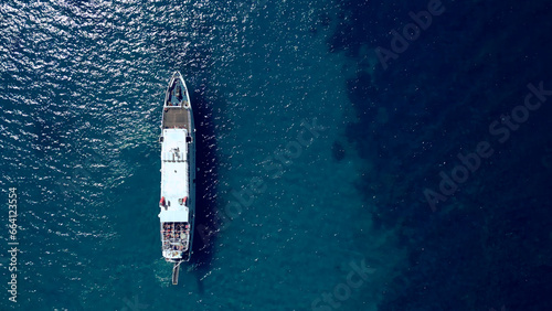 Vertical aerial view of white ferry ship in blue sea water