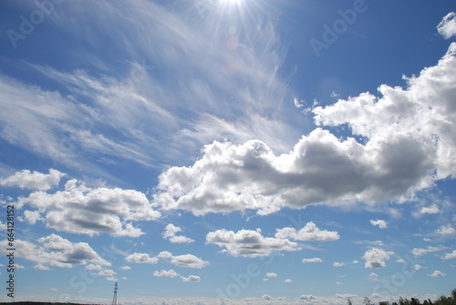 Sky landscape on a summer day. On a clear sunny day, multi-level clouds, cirrus high and cumulus low, slowly float in the light blue sky. Clouds of different shapes and sizes. © Andrew_Swarga