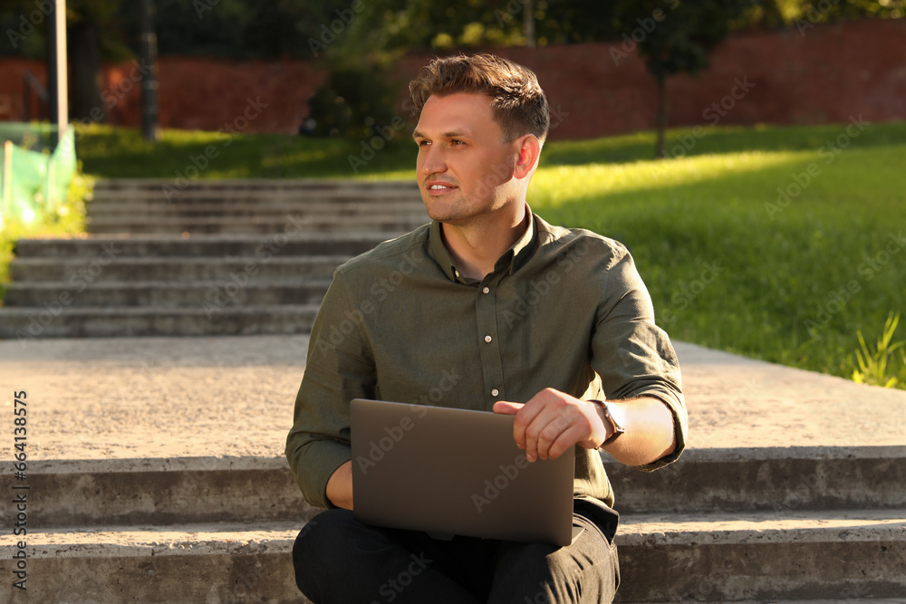Handsome man with laptop sitting on concrete stairs outdoors Handsome man with laptop sitting on concrete stairs outdoors