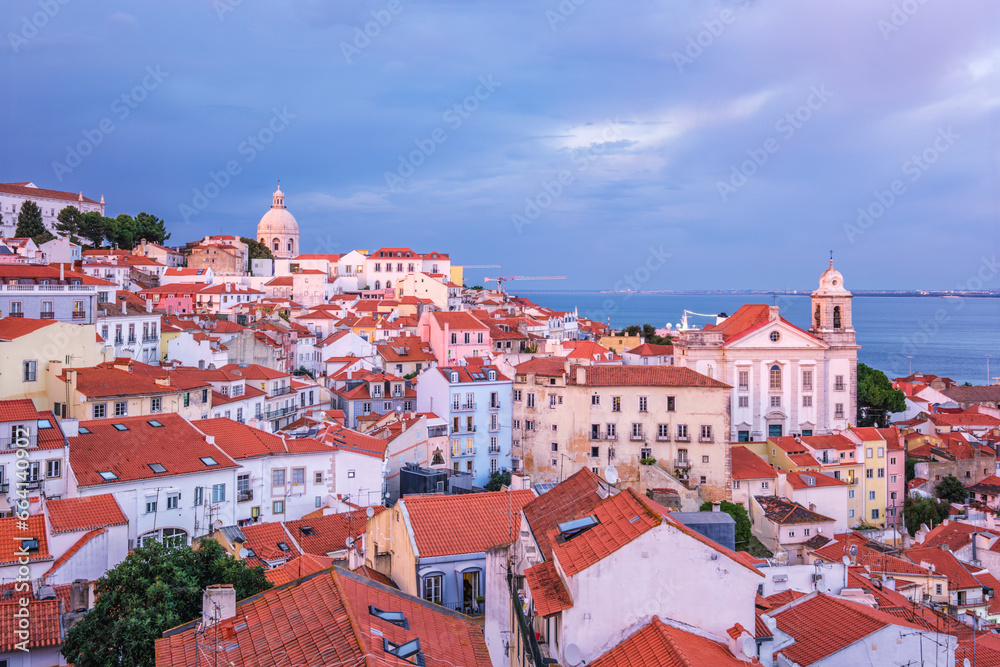 Obraz premium View of Lisbon famous view from Miradouro de Santa Luzia tourist viewpoint over Alfama old city district on sunset with dramatic overcast sky. Lisbon, Portugal.