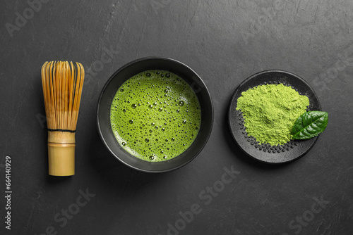 Cup of fresh matcha tea, bamboo whisk and green powder on black table, flat lay