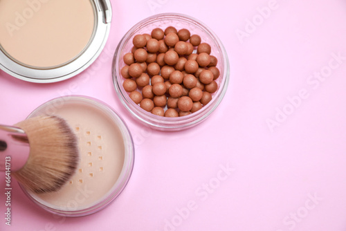 Applying face powder on brush on pink background, flat lay. Space for text