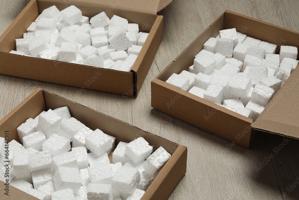 Open cardboard boxes with pieces of polystyrene foam on wooden floor. Packaging goods Open cardboard boxes with pieces of polystyrene foam on wooden floor. Packaging goods