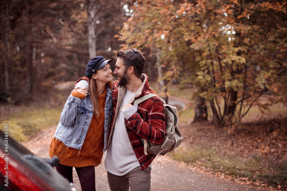 Loving young couple standing by a car in the park