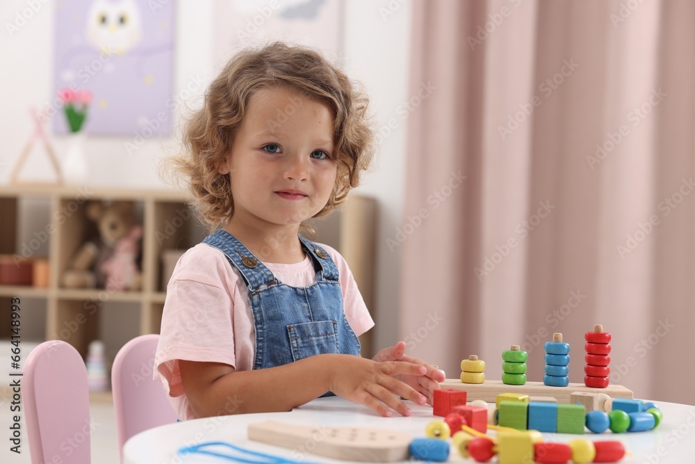 Motor skills development. Little girl playing with toys at table indoors Motor skills development. Little girl playing with toys at table indoors