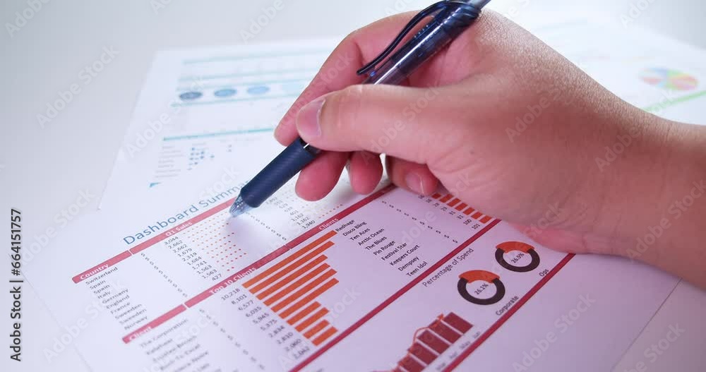 Close-up of businessman's hands with pen working at office desk and analyzing dashboard graphs and charts, profit report checking. Man hands with pen-filling papers Close-up of businessman's hands with pen working at office desk and analyzing dashboard graphs and charts, profit report checking. Man hands with pen-filling papers
