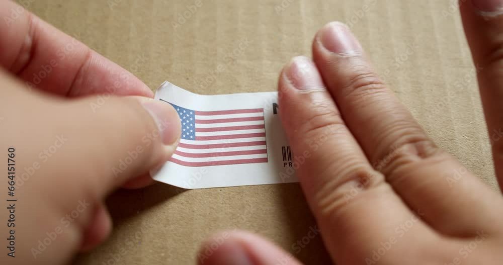 Hands applying MADE IN USA flag label on a shipping box with product premium quality barcode. Manufacturing and delivery. Product factory import and export.