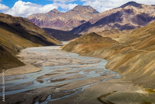 A breathtaking view of the Spiti Valley showcases the meandering Spiti River set against majestic multi-colored mountains. The vast and rugged landscape is a testament to nature s grandeur.