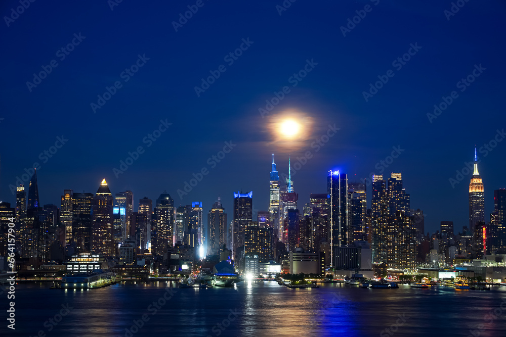 Hudson River reflects the lights and New York Skyline at night