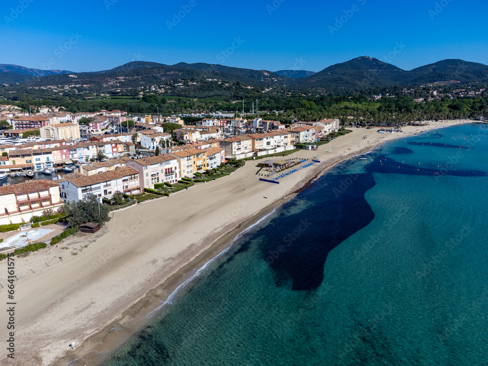 Arial view on blue water of Gulf of Saint-Tropez, sandy beach, houses in Port Grimaud, village on Mediterranean sea with yacht harbour, Provence, summer in France