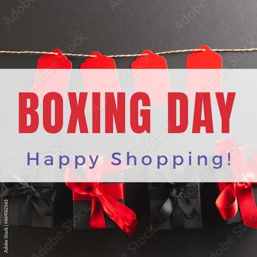 Composite of boxing day, happy shopping text over gift boxes and red tags on black background