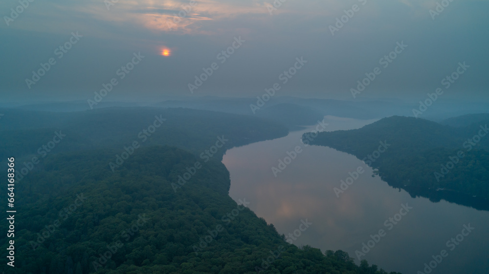 An aerial view of Esson Lake reflecting the sky on a hazy day in the summer during sunset An aerial view of Esson Lake reflecting the sky on a hazy day in the summer during sunset