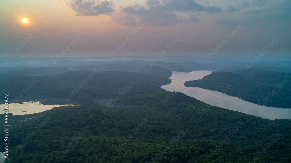 An aerial view of Esson Lake reflecting the sky on a hazy day in the summer during sunset