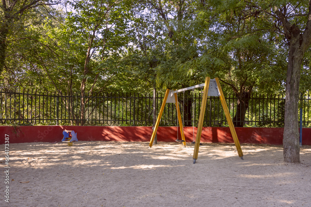 Fototapeta premium swing with chains on a playground with wooden arms and sand on the ground