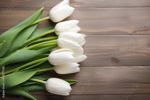 White tulips on wood table.