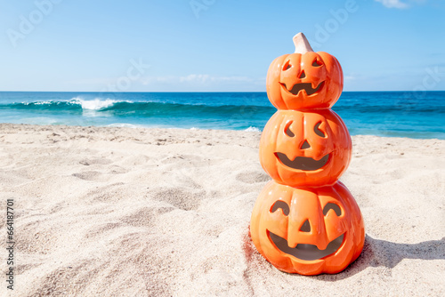 Halloween beach background with three smiling pumpkins © ellensmile
