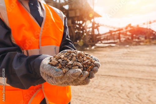 Worker engineer hold gravel in hand, checks quality at sand quarry. Industrial construction site concept