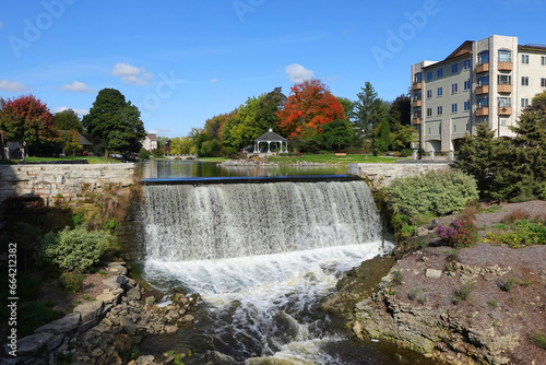 Fototapeta Naklejka Na Ścianę i Meble -  Scenic Downtown Park with Dam, Waterfall, Pavilion, and Fall Foliage