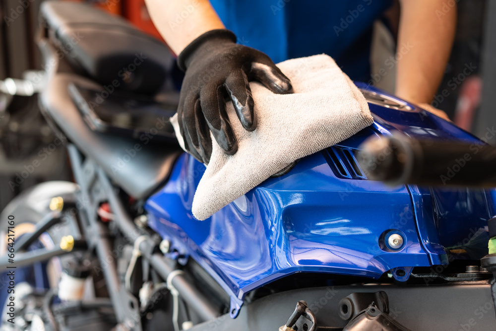 Biker man cleaning motorcycle , Polished and coating wax on fuel tank at garage. motorcycle maintenance and repair concept.