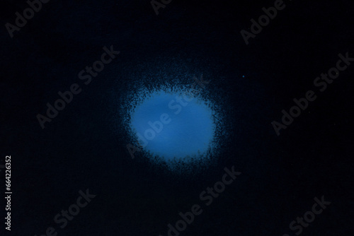 a blue spray paint stain on a black paper background