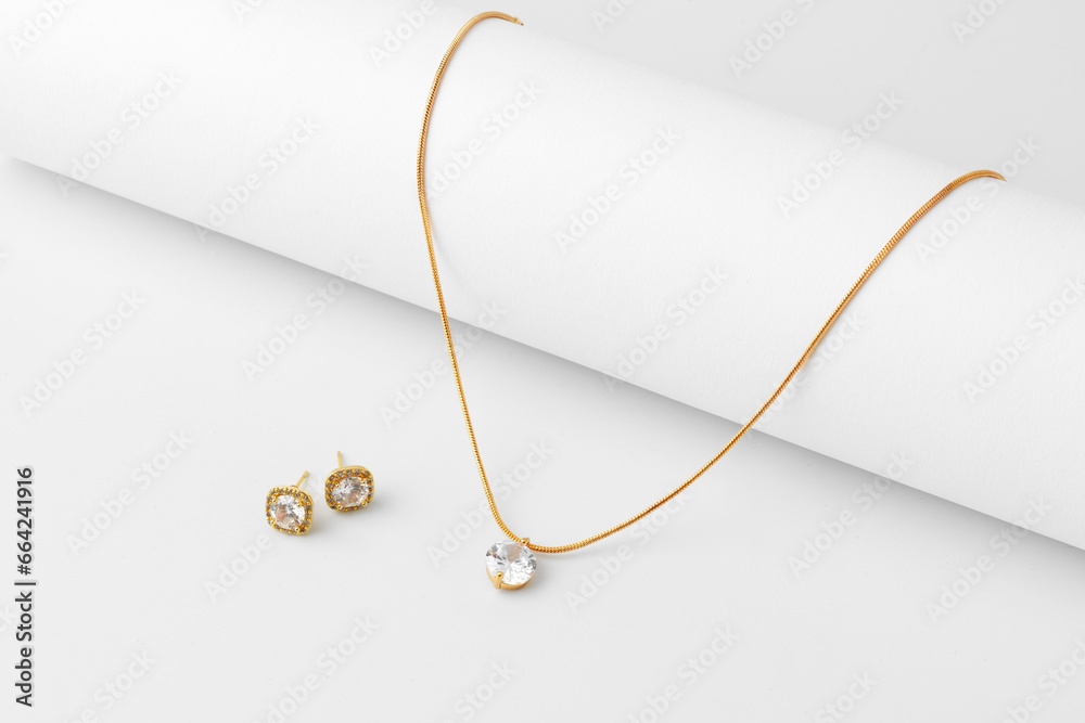 Golden necklace and diamond earrings on white paper background - obrazy, fototapety, plakaty 