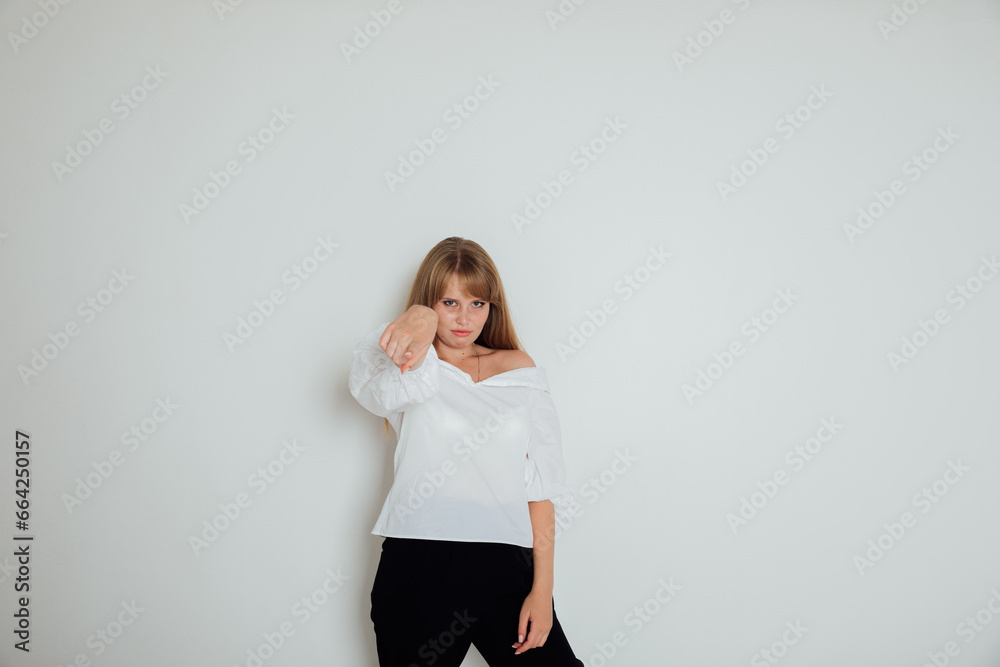Woman showing index finger on light background in room Woman showing index finger on light background in room
