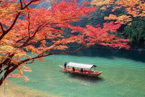  Boatman punting the boat for tourists to enjoy the autumn view along the bank of Hozu river in Arashiyama Kyoto, Japan.