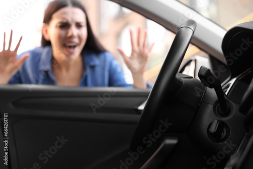 Automobile lockout, key forgotten inside, selective focus. Emotional woman looking through car window photo