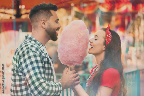 Happy couple eating cotton candy at funfair