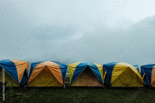 Tent in camping with flog and mountain view. Tent on campsite by the hill in rainy day. Tent wet after rain. Water droplets on the tent. Khao Kho, Phetchabun Province in Thailand. photo