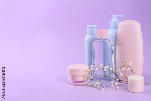 Different skin care products for baby and gypsophila on violet background. Space for text