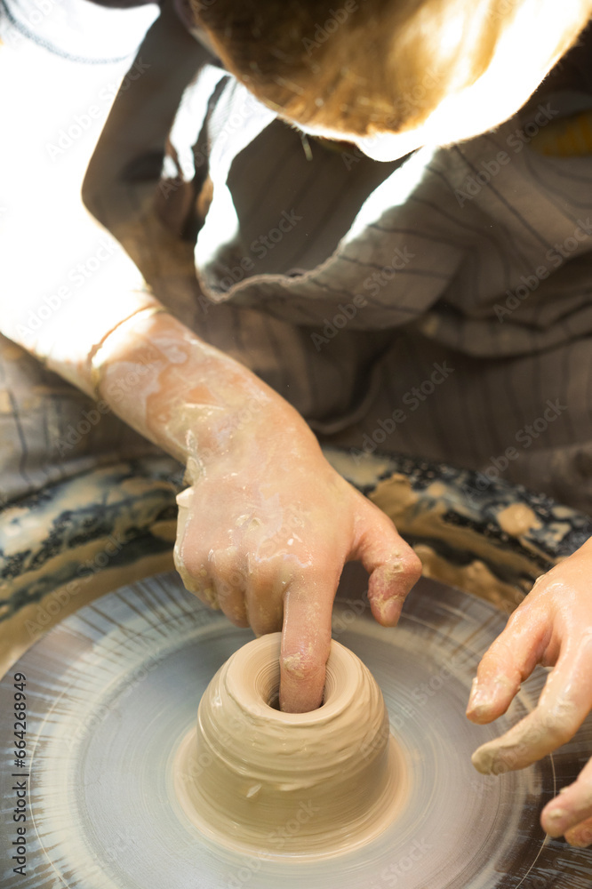 Hands of potter stained with pottery clay. Person is making pottery or ceramic on potter's wheel