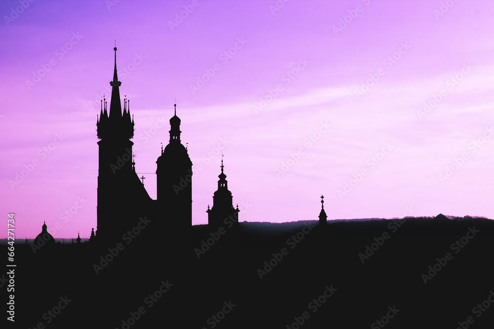 Black silhouette St. Mary Basilica in Krakow and panorama of the city center against a background of sunset and a fantastic purple sky