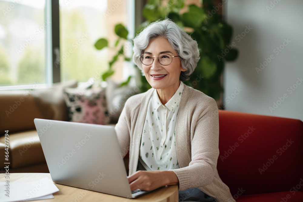 Happy woman working remote from home office using laptop to take notes Middle-aged business woman in her 60s smiling using a computer watching a webinar. Happy woman working remote from home office using laptop to take notes Middle-aged business woman in her 60s smiling using a computer watching a webinar.