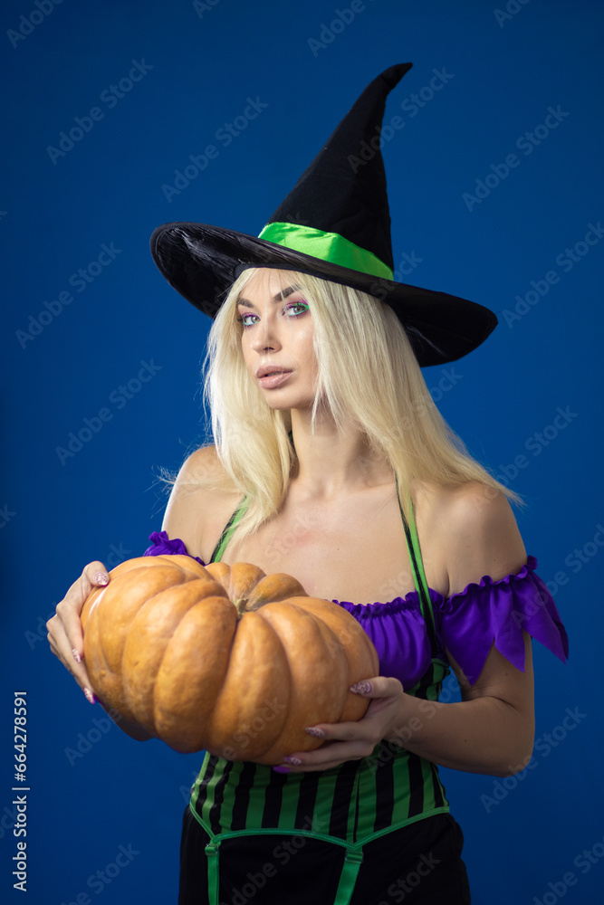 Blonde woman in a witch costume holding pumpkin in her hands Blonde woman in a witch costume holding pumpkin in her hands