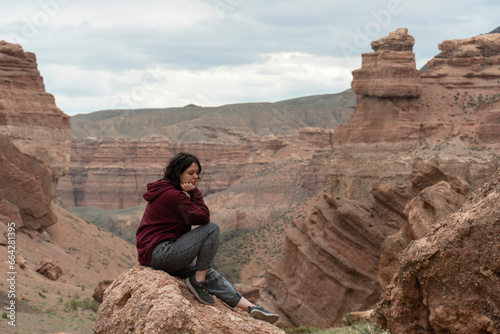 A young woman sits on a rock in the Central Asian Canyon, Charyn, Kazakhstan