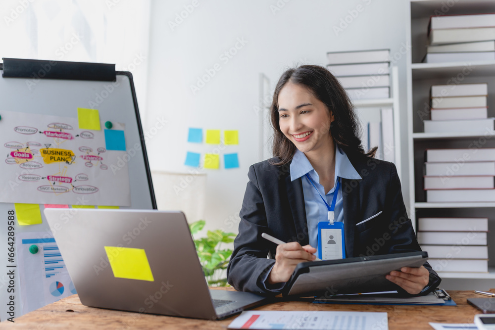 Asian business woman manager or company worker holding accounting document, checking financial data or marketing report working in office with laptop. Accountant consults on some docum Asian business woman manager or company worker holding accounting document, checking financial data or marketing report working in office with laptop. Accountant consults on some docum