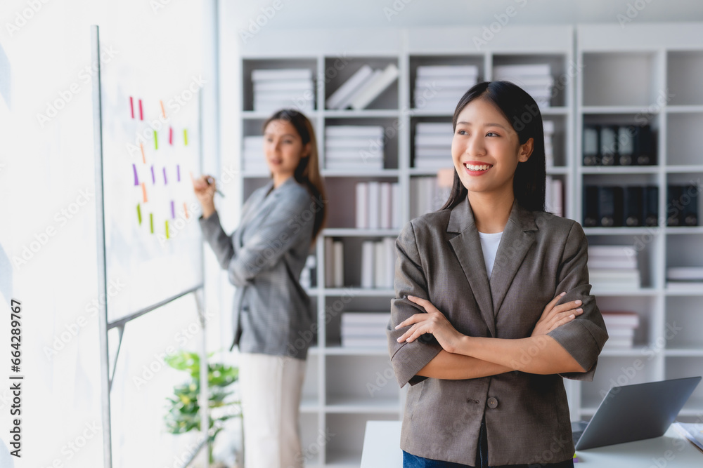 Smiling confident asian businesswoman with arms crossed standing in office.