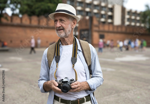 Senior Caucasian tourist holding camera during visitting Tha Pae Gate, Chiangmai Thailand during summer vacation  photo