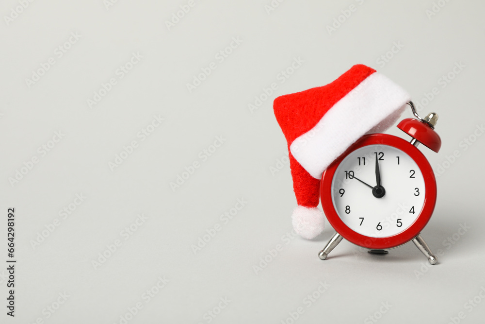 A clock with a Santa hat with a New Year's decoration. - obrazy, fototapety, plakaty 