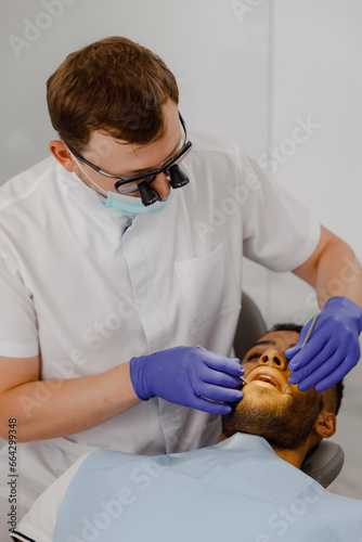 At dental clinic the patient on the dentist chair laying down he make a tooth check appointment the dentist check every teeth