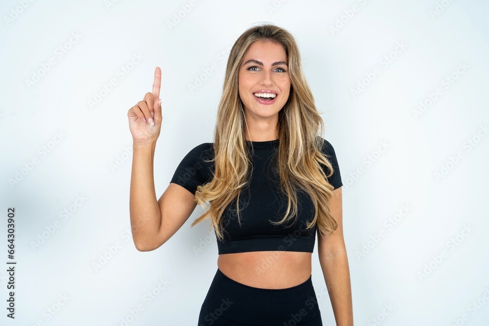 caucasian woman wearing sport clothes showing and pointing up with finger number one while smiling confident and happy. caucasian woman wearing sport clothes showing and pointing up with finger number one while smiling confident and happy.
