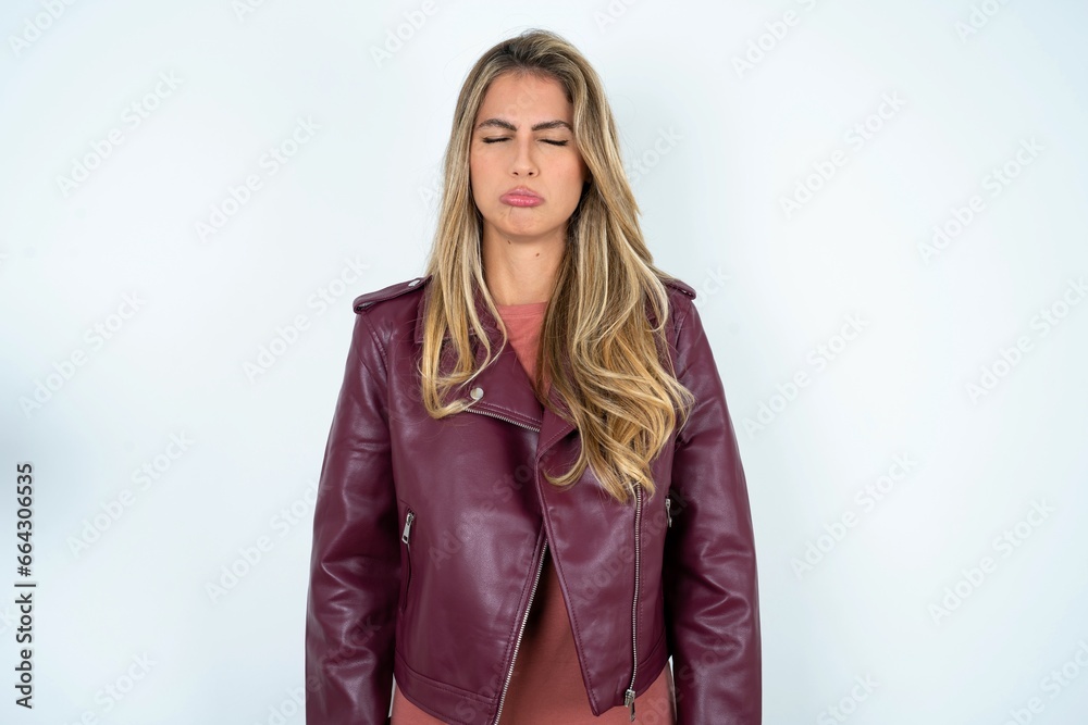 Dismal gloomy rejected Beautiful young woman wearing jacket has problems and difficulties, curves lower lip and closes eyes in despair, being in depression Dismal gloomy rejected Beautiful young woman wearing jacket has problems and difficulties, curves lower lip and closes eyes in despair, being in depression